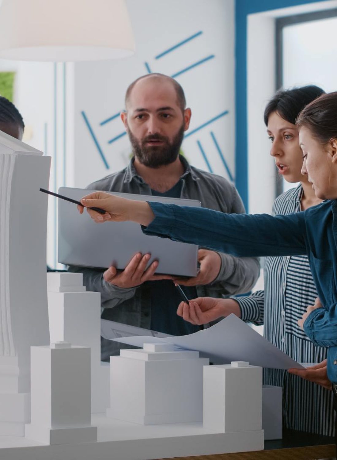multi-ethnic-people-working-with-laptop-tablet-building-model-architecture-project-coworkers-doing-teamwork-design-maquette-construction-layout-with-blueprints (1)